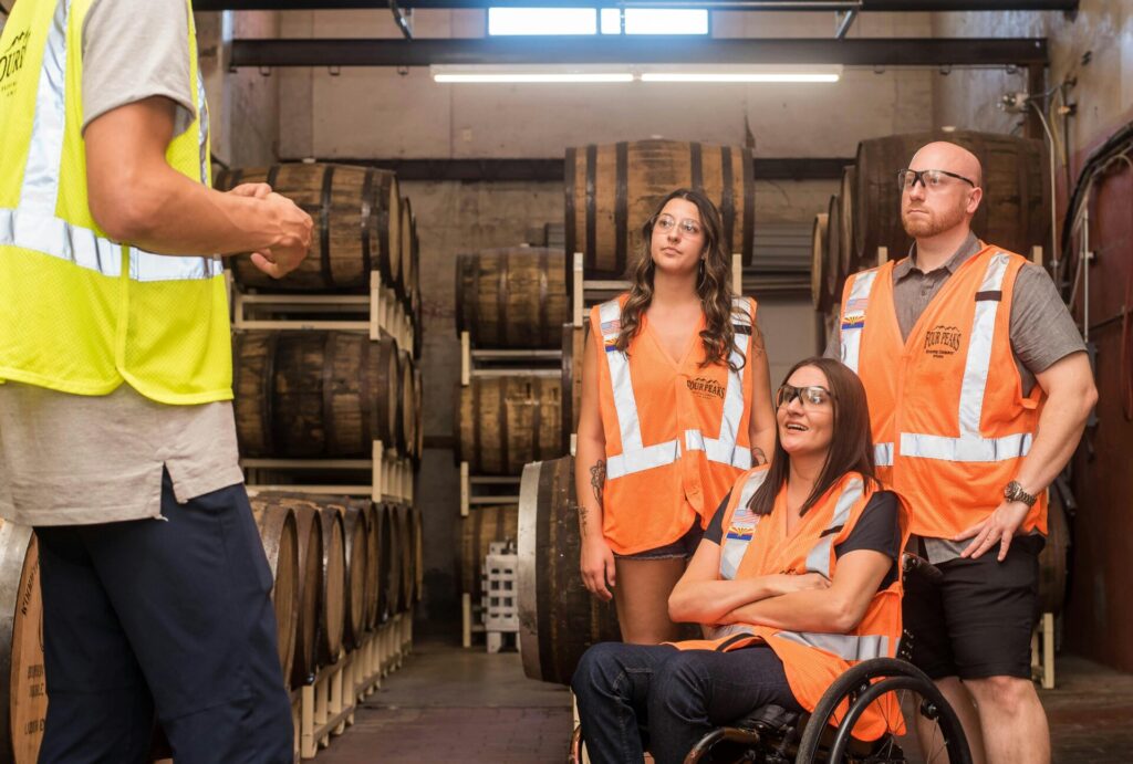 three people one girl in a wheelchair getting training in a wine setting