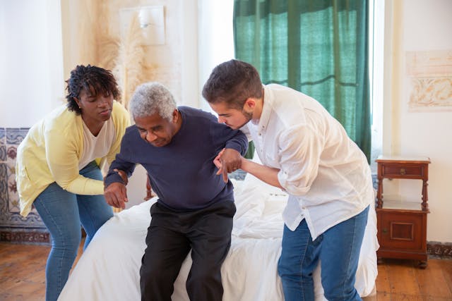 who case workers helping a elderly individual get to a bed