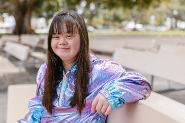 girl with disabilities sitting outside on a park bench