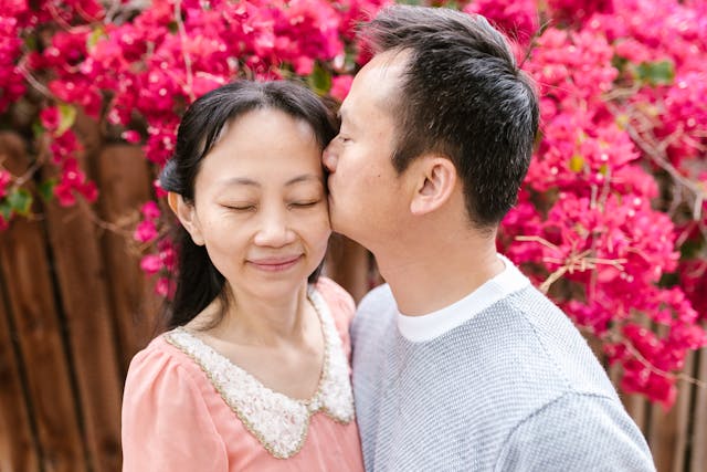 a elderly couple kissing by flowers