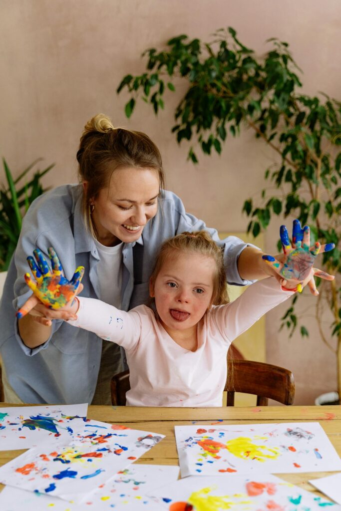 mother helping her disabled daughter paint